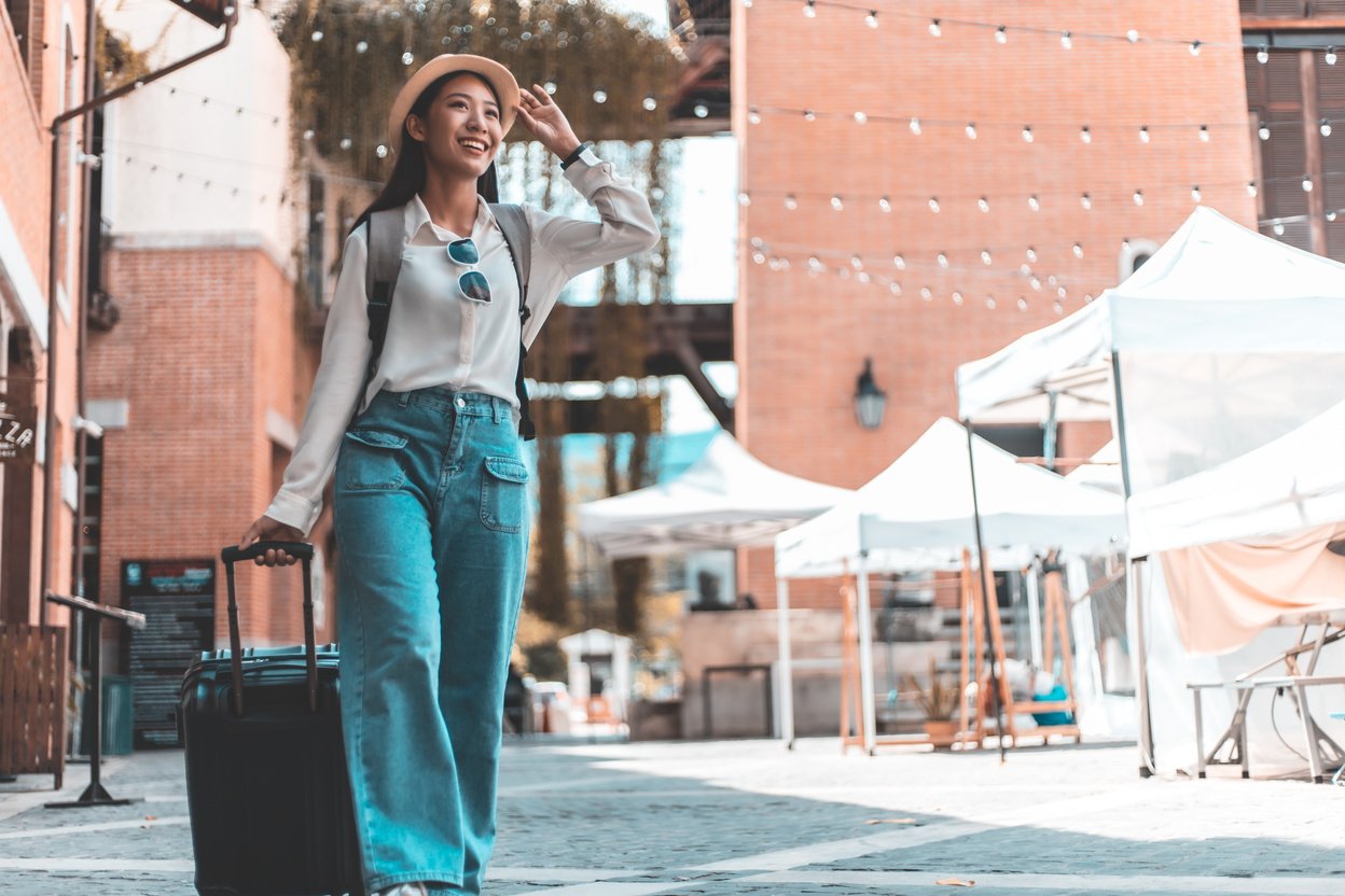 Smiling Woman with Black Suitcase Walking Outdoors